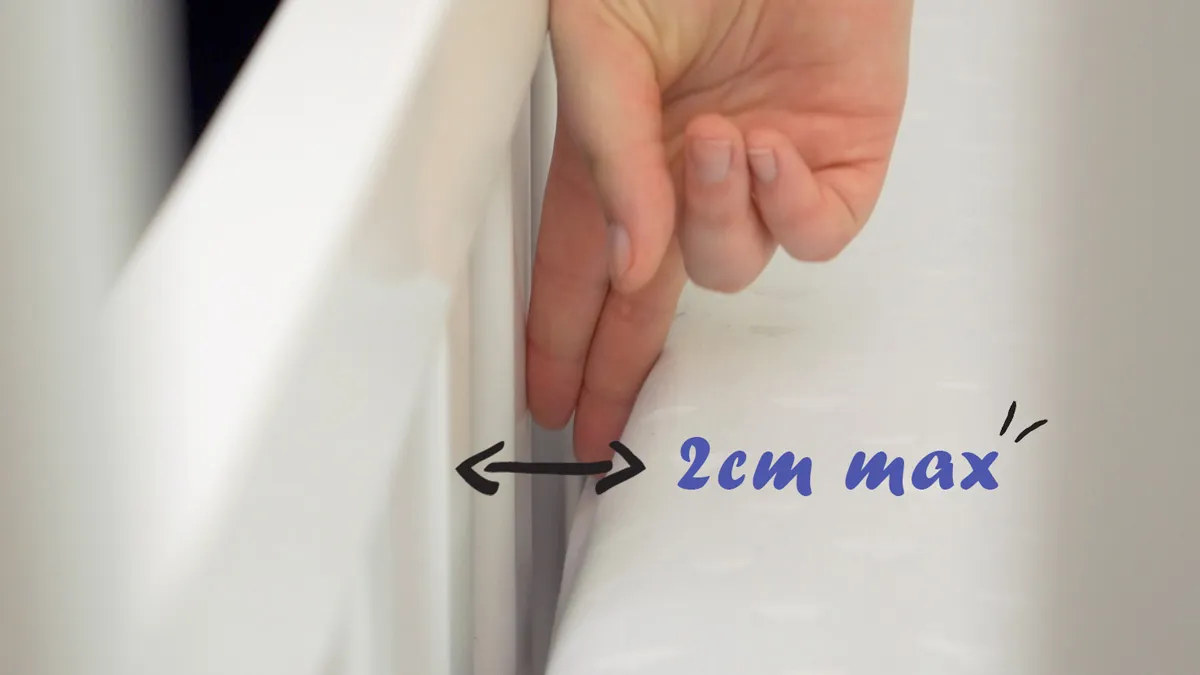 Cot Mattress Fit, Red Nose Safety Recommendation Hand checking the gap between a cot mattress and frame
